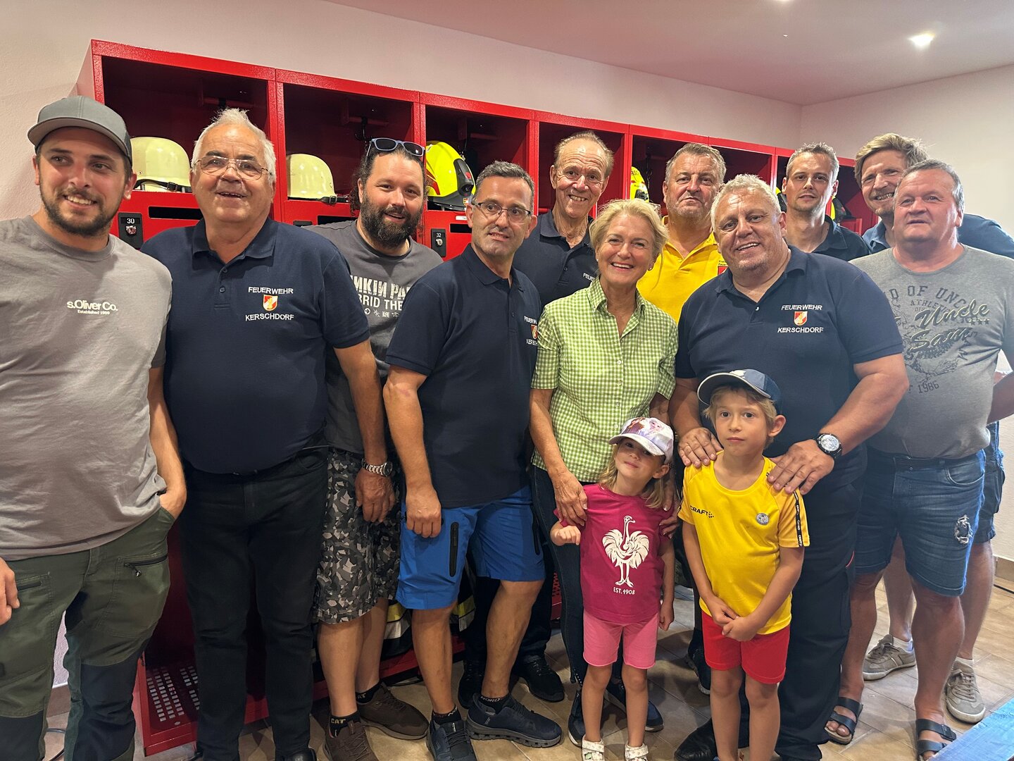 Feuerwehr Kerschdorf mit Kindern vor roten Spinden mit Helmen