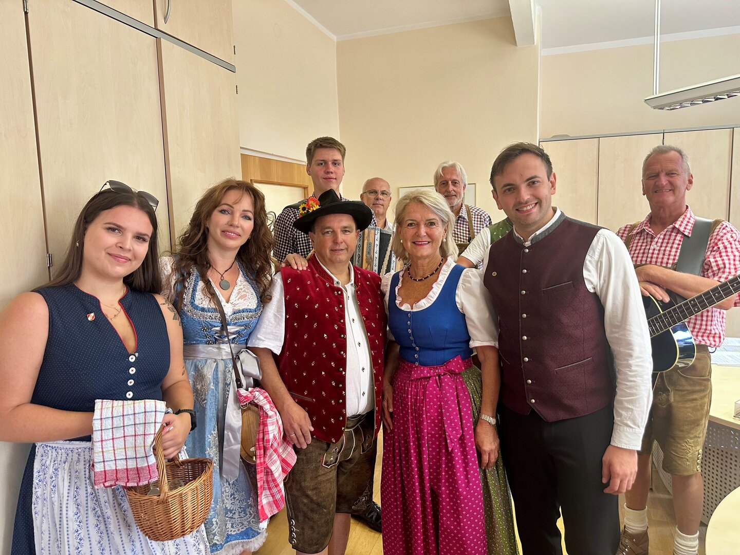 Trachtengruppe mit Musikanten in Tracht, ein Mann mit Gitarre, in einem Raum